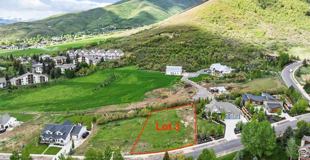 Aerial view of residential area with property boundaries highlighted and a mountainous background