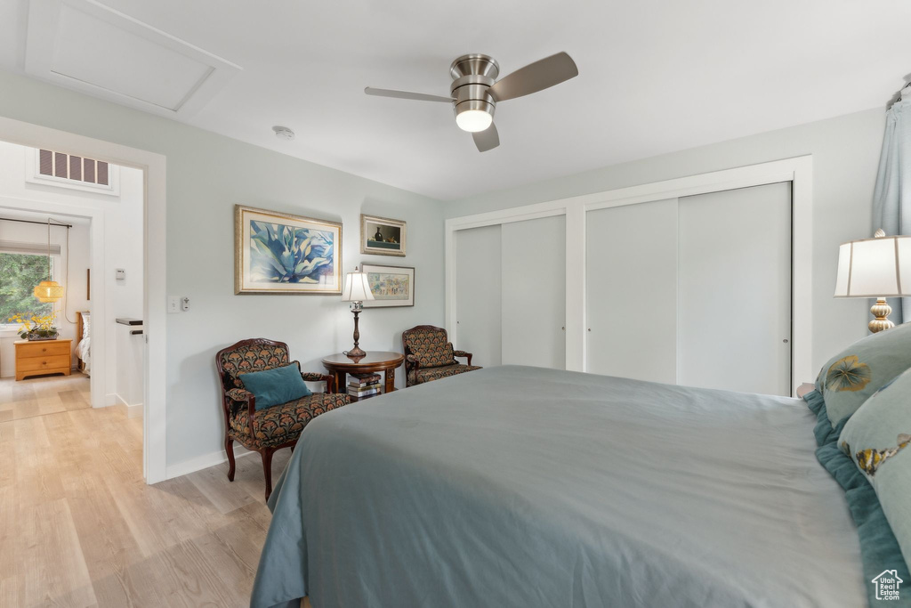 Bedroom with two closets, light wood-style flooring, baseboards, attic access, and a ceiling fan