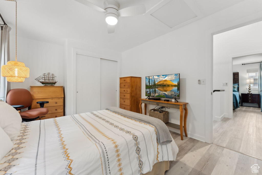 Bedroom featuring attic access, wood finished floors, a closet, ceiling fan, and baseboards