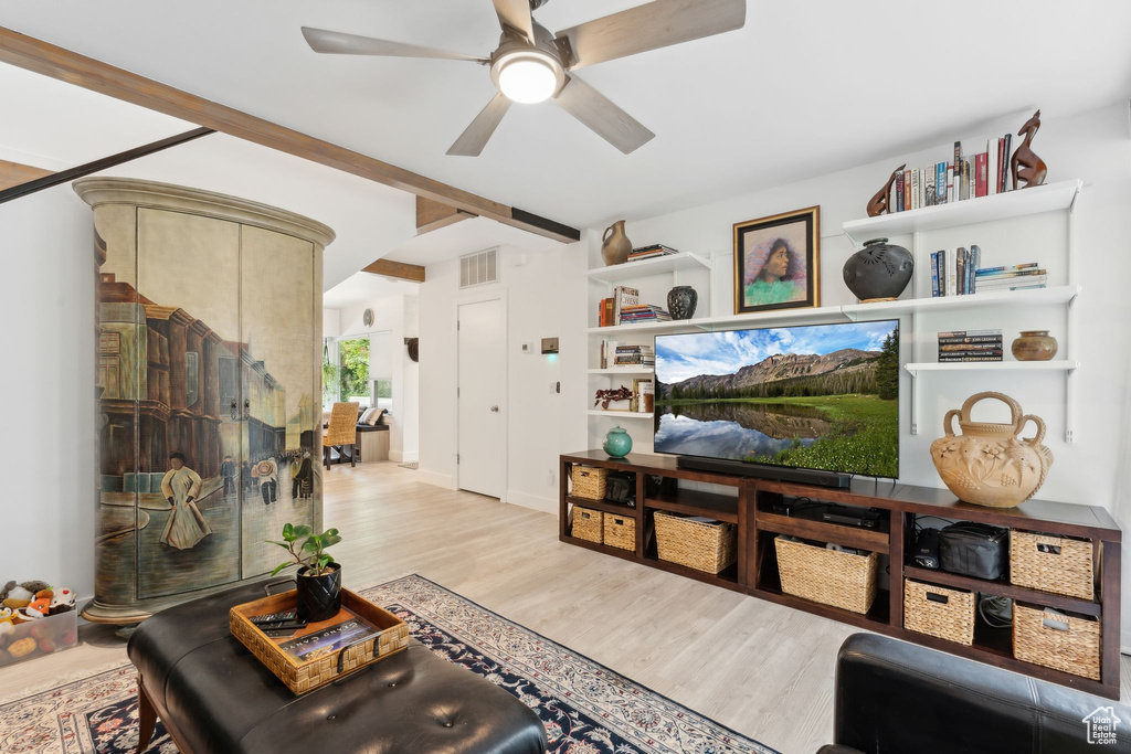 Living area featuring a ceiling fan, light wood-type flooring, and beamed ceiling