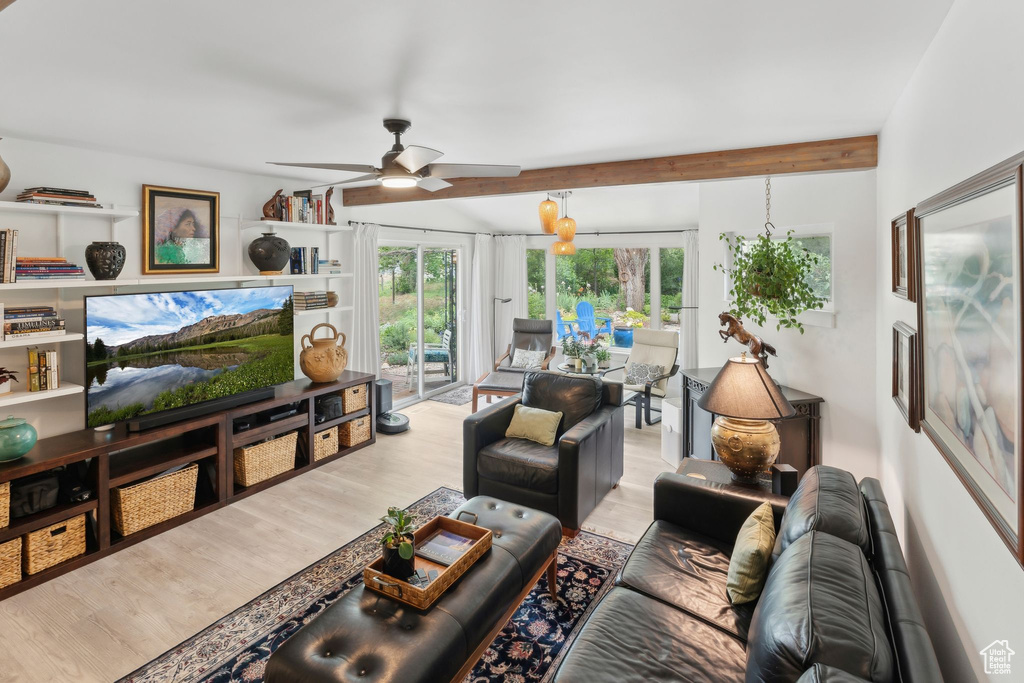 Living area featuring ceiling fan, wood finished floors, and beamed ceiling