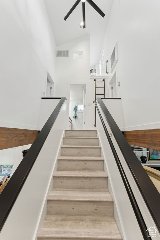 Stairway featuring high vaulted ceiling, ceiling fan, wood finished floors, and baseboards