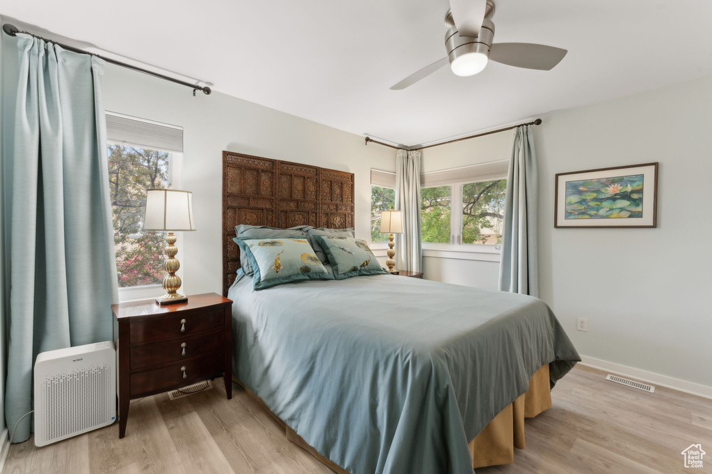 Bedroom with multiple windows, light wood-type flooring, and a ceiling fan