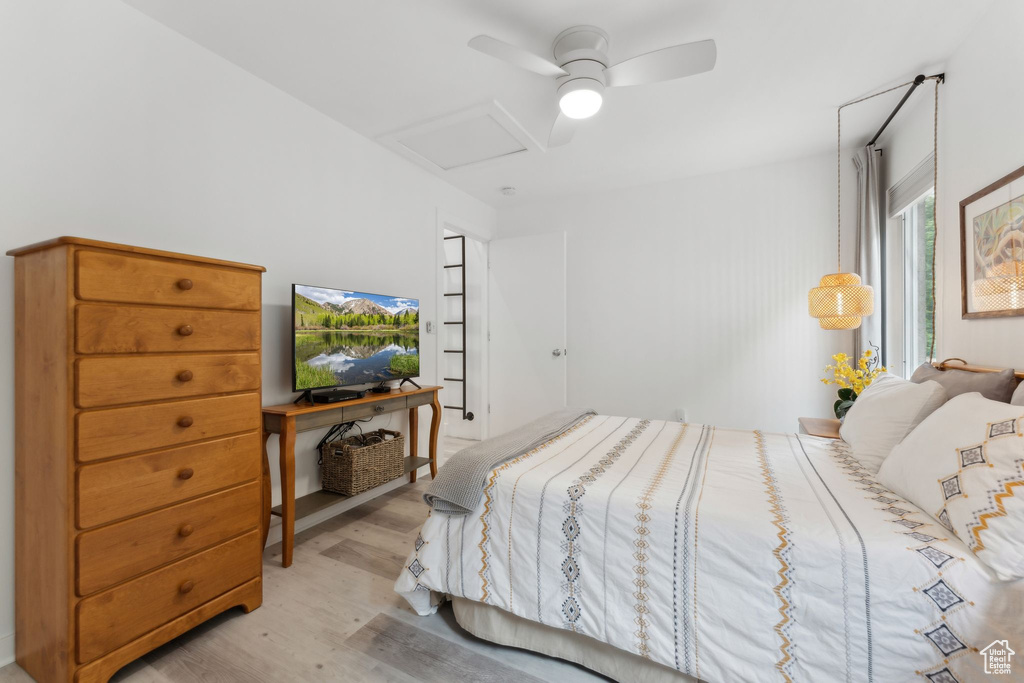 Bedroom with attic access, light wood-style floors, and a ceiling fan