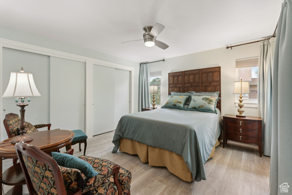Bedroom with two closets, light wood-type flooring, and ceiling fan