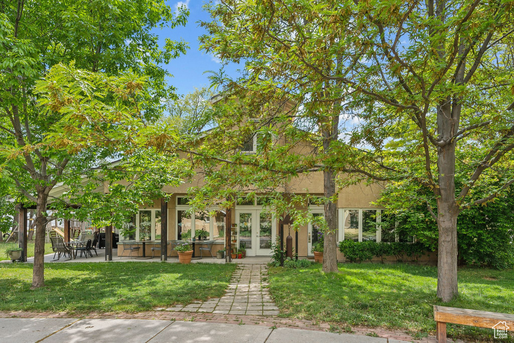 Obstructed view of property featuring french doors, a front lawn, a patio area, and stucco siding