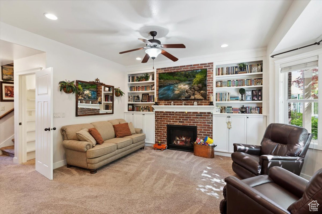 Carpeted living area featuring a ceiling fan, a brick fireplace, built in features, recessed lighting, and stairway