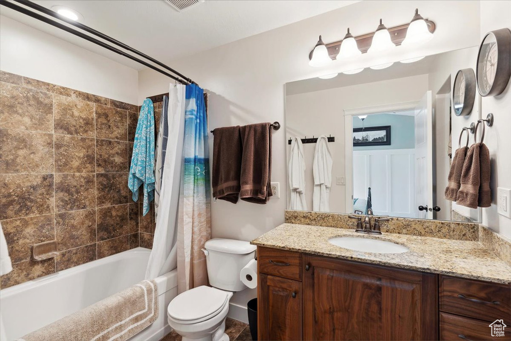 Full bathroom featuring toilet, shower / bath combination with curtain, and vanity