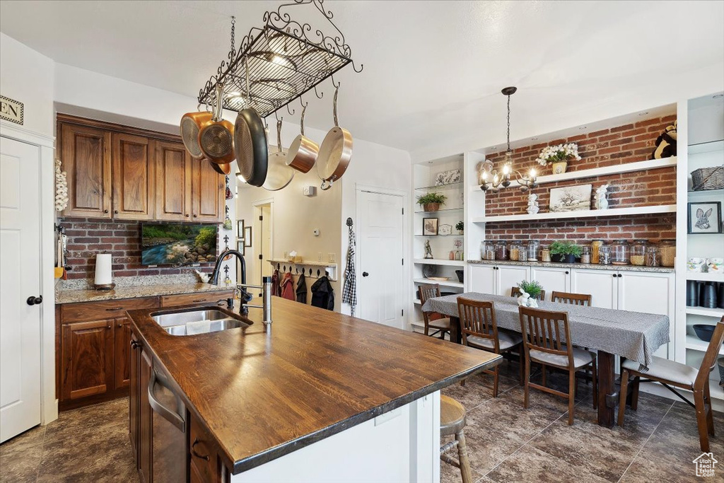 Kitchen with a sink, stainless steel dishwasher, an island with sink, a kitchen bar, and open shelves