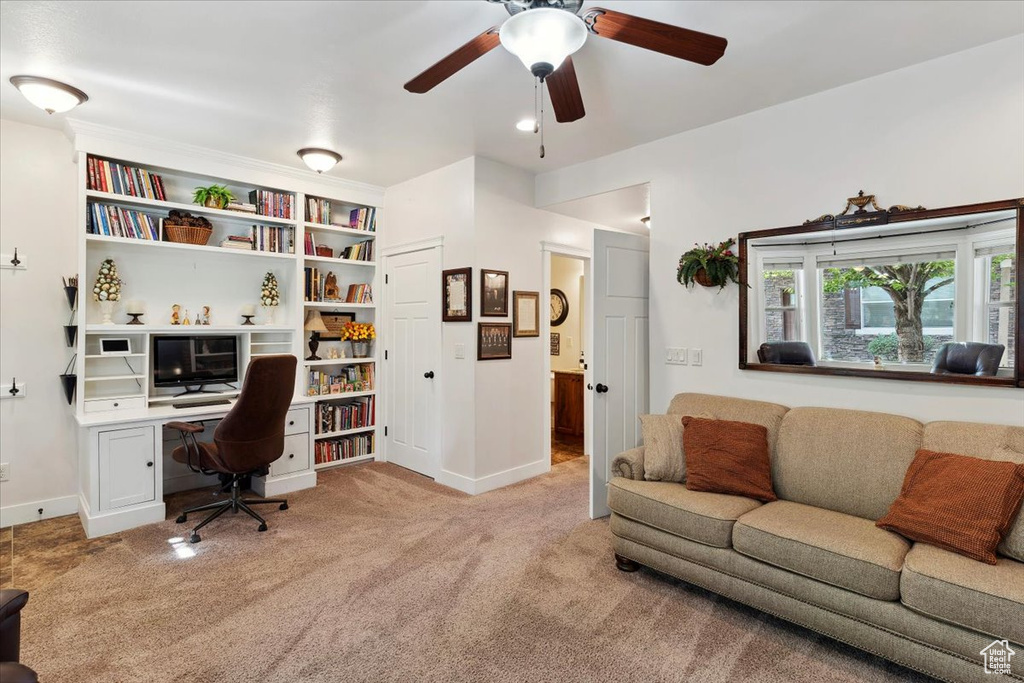 Carpeted home office with a ceiling fan and baseboards