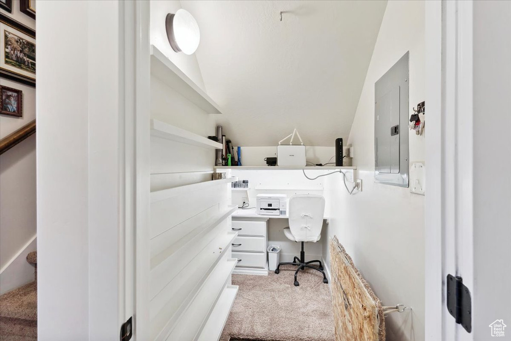 Office area with electric panel, carpet flooring, vaulted ceiling, and built in study area