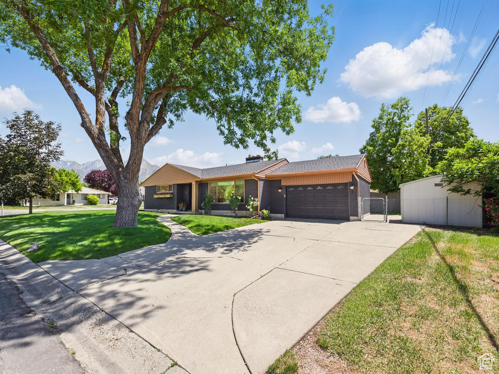 Ranch-style home with a garage, driveway, and a gate