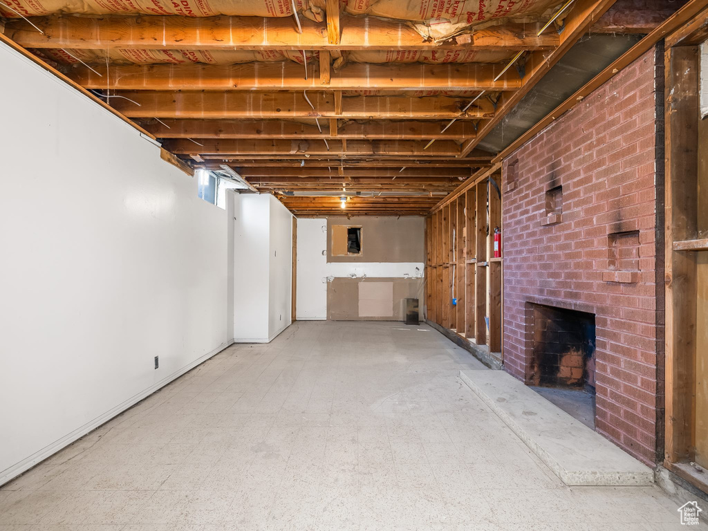 Unfinished basement featuring a brick fireplace