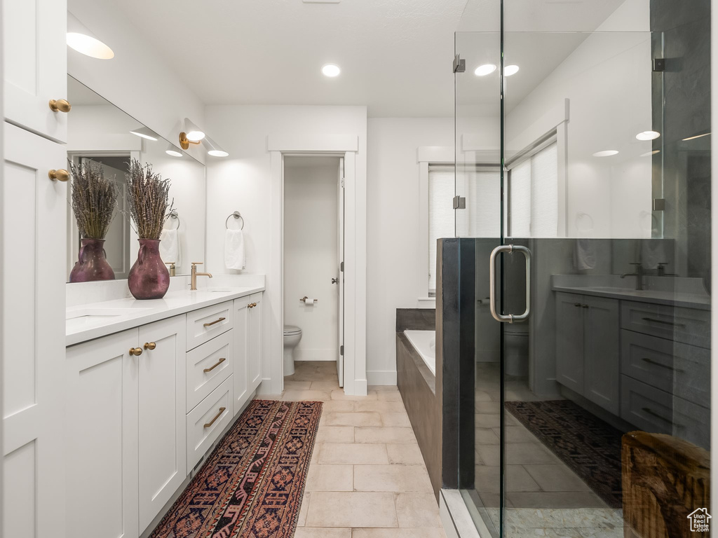 Bathroom with double vanity, a garden tub, a shower stall, toilet, and recessed lighting