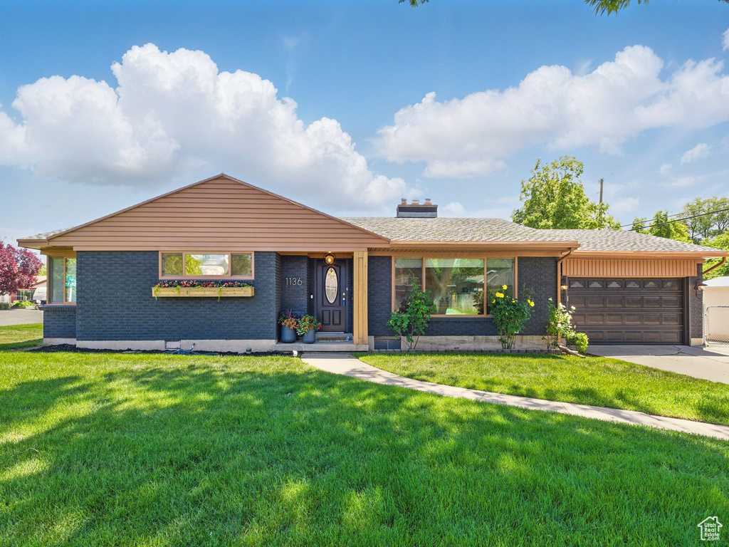 Ranch-style home with brick siding, a front yard, an attached garage, and a chimney