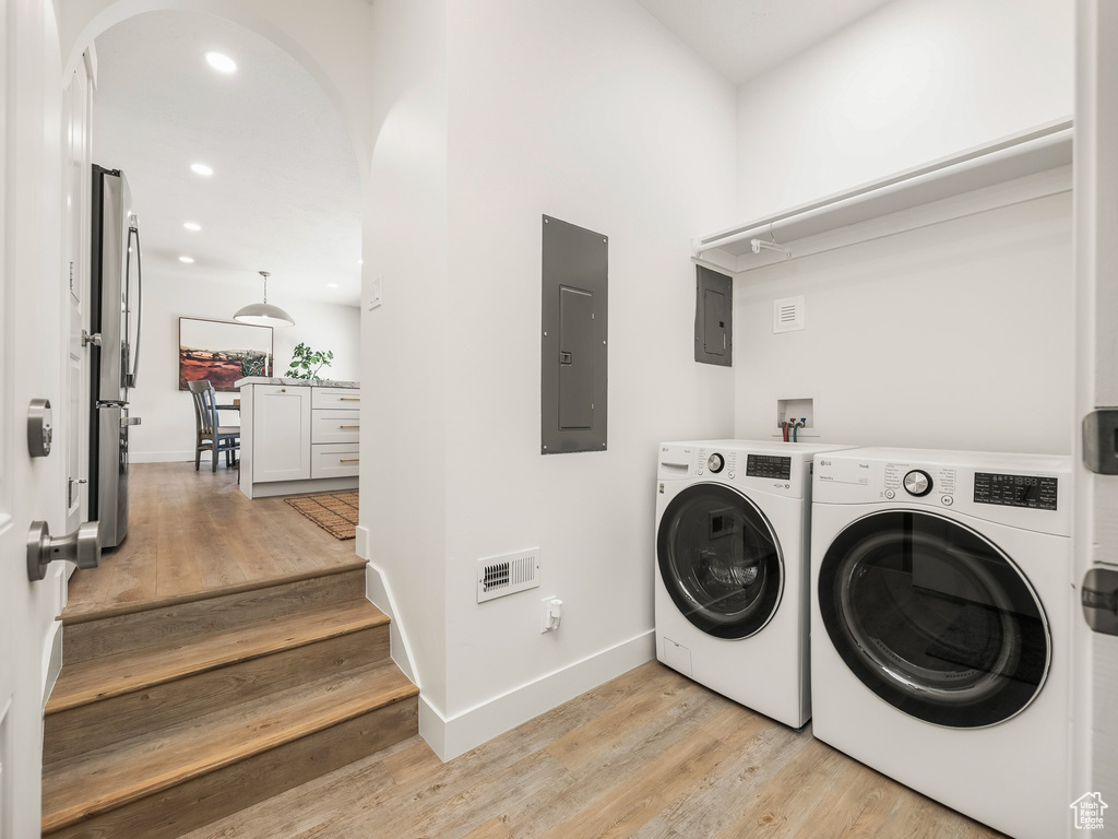 Laundry area featuring electric panel, arched walkways, light wood-style flooring, and recessed lighting