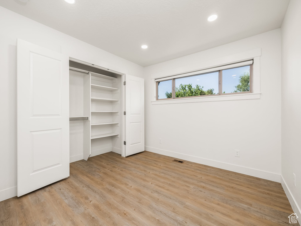 Unfurnished bedroom with baseboards, light wood finished floors, recessed lighting, and a closet