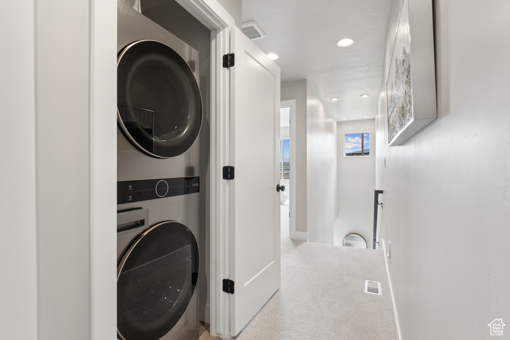 Laundry area featuring stacked washing machine and dryer, carpet flooring, recessed lighting, and baseboards