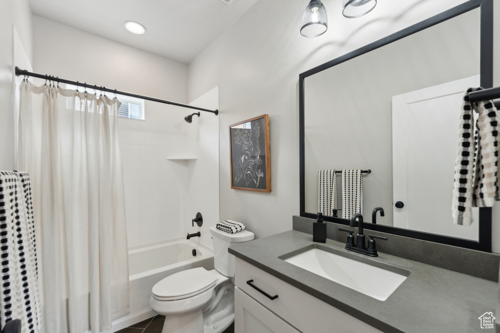 Bathroom with shower / bathtub combination with curtain, vanity, and toilet