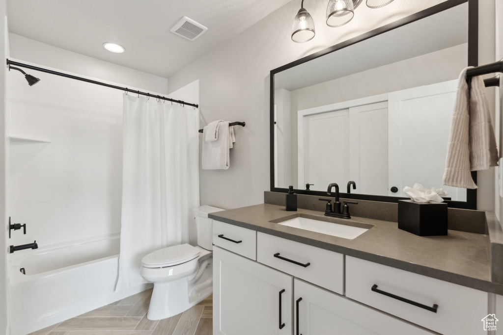 Bathroom featuring toilet, vanity, and shower / bath combo with shower curtain