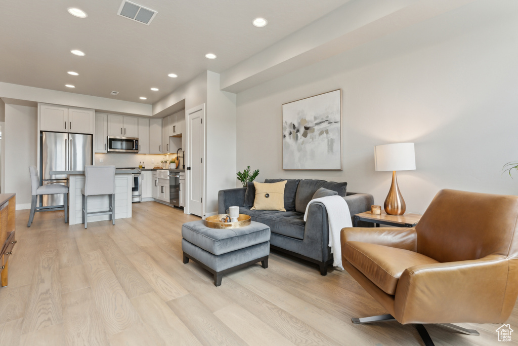 Living area featuring recessed lighting, light wood-style floors, and baseboards