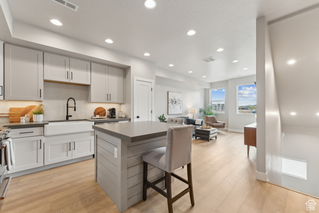 Kitchen featuring a sink, a kitchen island, light wood-style floors, open floor plan, and recessed lighting