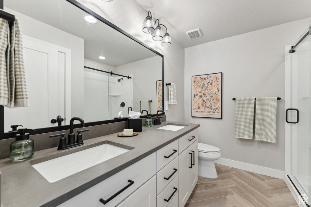 Full bath with a shower stall, toilet, baseboards, double vanity, and recessed lighting