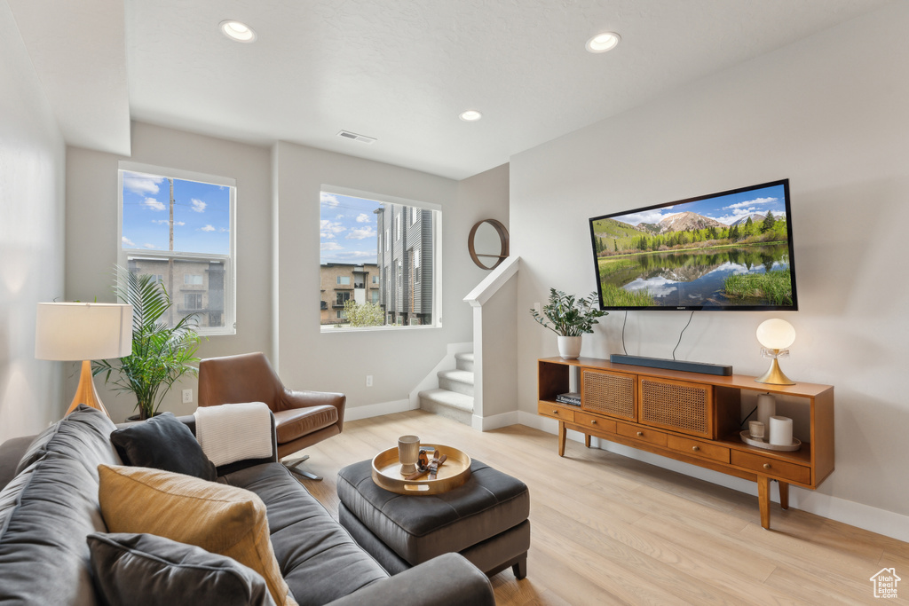 Living area featuring light wood-style floors, stairs, baseboards, and recessed lighting