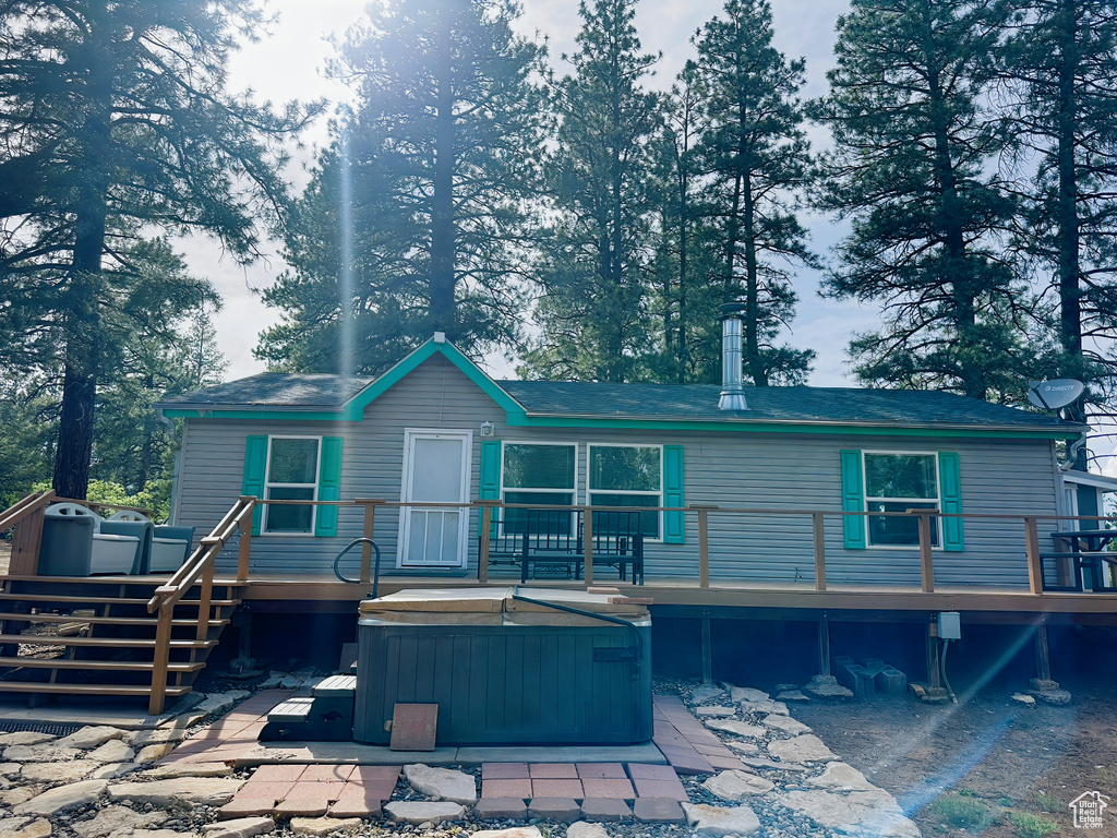 Rear view of property featuring a hot tub, a deck, and a patio