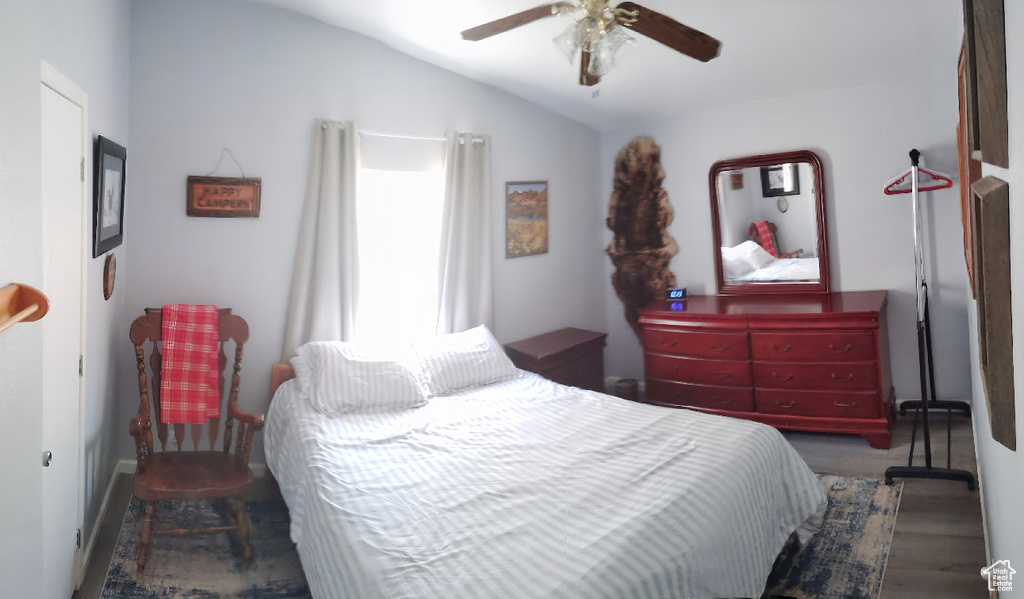 Bedroom with vaulted ceiling, wood finished floors, and ceiling fan