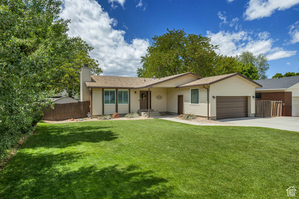 Ranch-style home featuring an attached garage, concrete driveway, a chimney, and roof with shingles