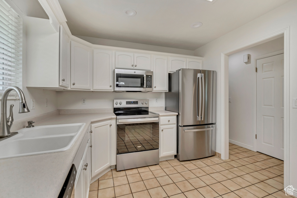 Kitchen with stainless steel appliances, a sink, white cabinets, light tile patterned floors, and recessed lighting