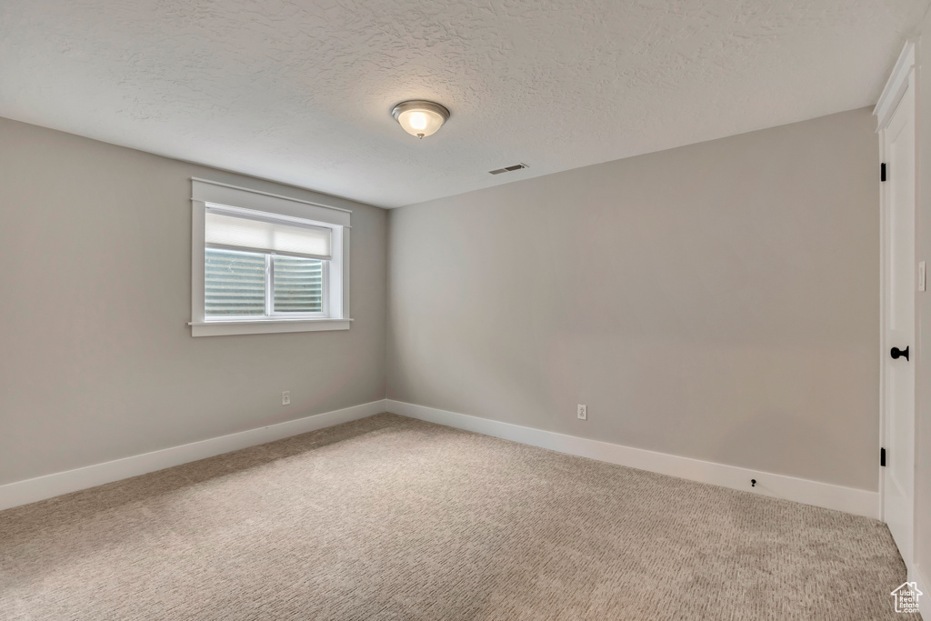 Unfurnished room featuring carpet, a textured ceiling, and baseboards