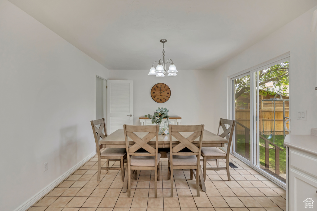 Dining space with a chandelier, light tile patterned floors, and baseboards