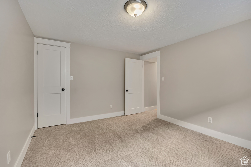 Unfurnished room featuring light colored carpet, a textured ceiling, and baseboards