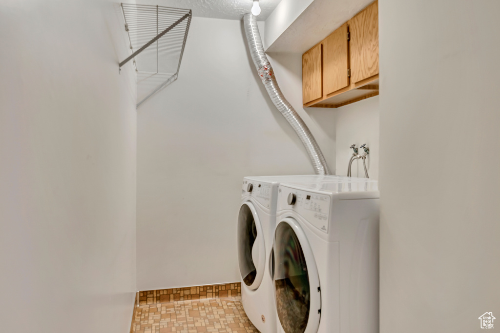 Laundry room featuring washer and dryer, cabinet space, and baseboards