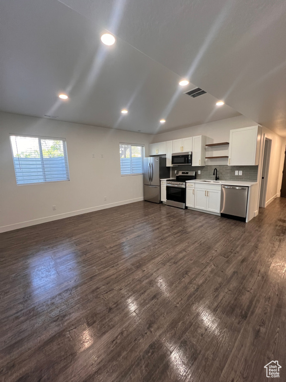 Kitchen featuring stainless steel appliances, a sink, white cabinets, light countertops, and baseboards