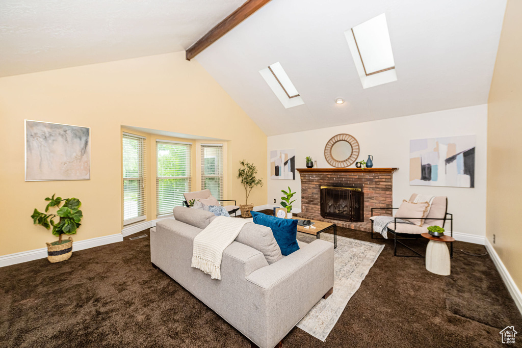 Living area featuring dark colored carpet, a fireplace, a skylight, beamed ceiling, and baseboards