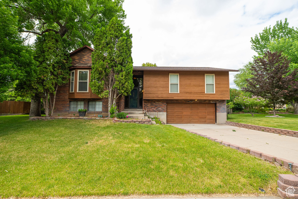 Raised ranch featuring an attached garage and concrete driveway