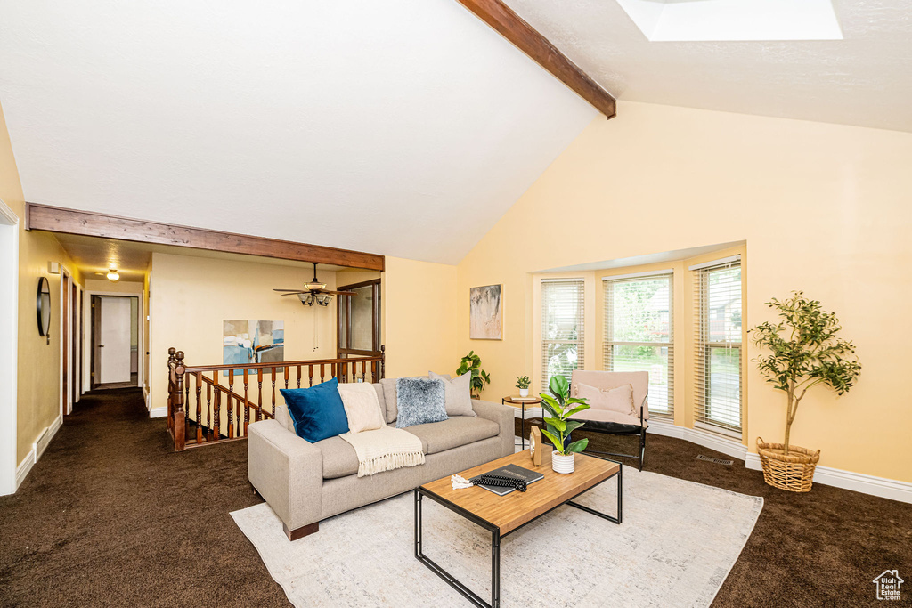 Living room featuring carpet floors, beamed ceiling, a skylight, high vaulted ceiling, and baseboards