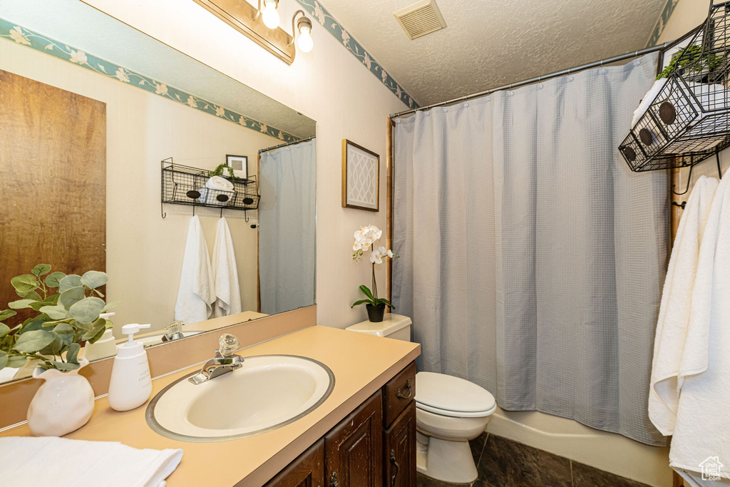 Full bath featuring a textured ceiling, toilet, and vanity