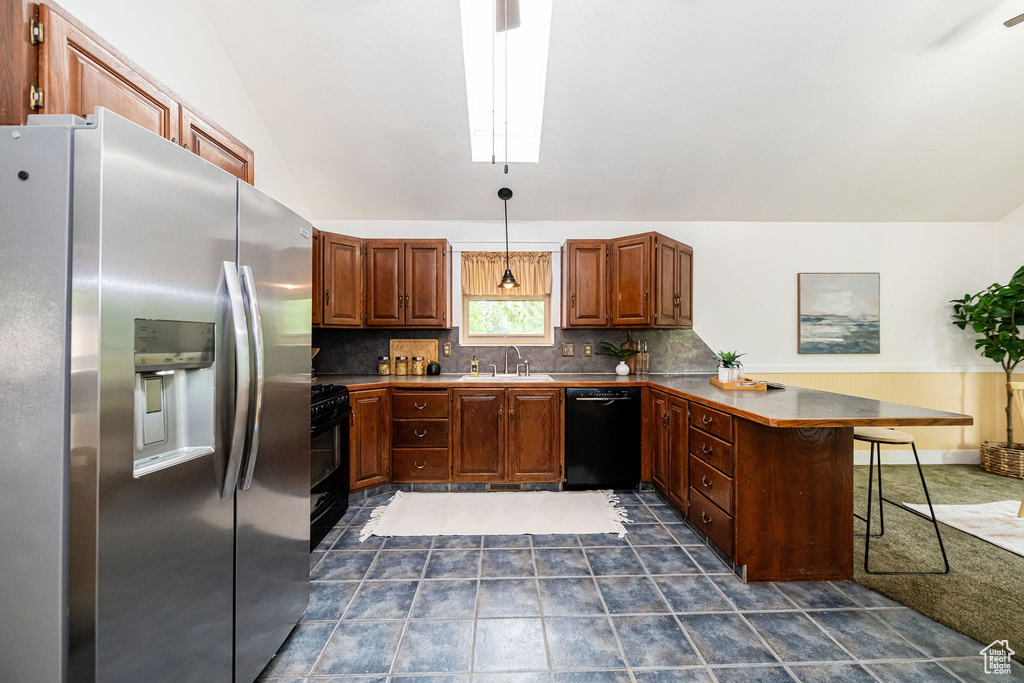 Kitchen with black appliances, a peninsula, backsplash, a kitchen breakfast bar, and lofted ceiling