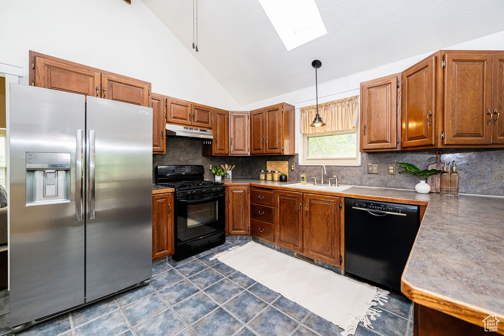 Kitchen with black appliances, a skylight, under cabinet range hood, backsplash, and a sink