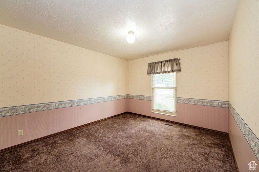 Unfurnished room featuring carpet floors, wallpapered walls, and a textured ceiling