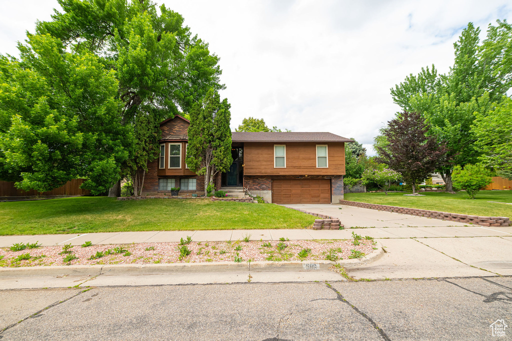 Raised ranch with concrete driveway, a garage, and brick siding