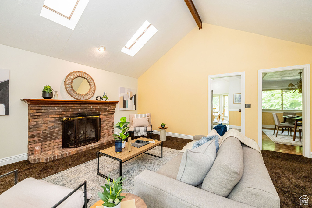 Living room with a skylight, baseboards, a brick fireplace, beamed ceiling, and carpet