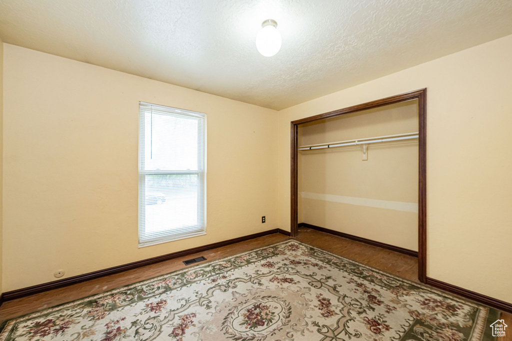 Unfurnished bedroom with a closet, a textured ceiling, and baseboards