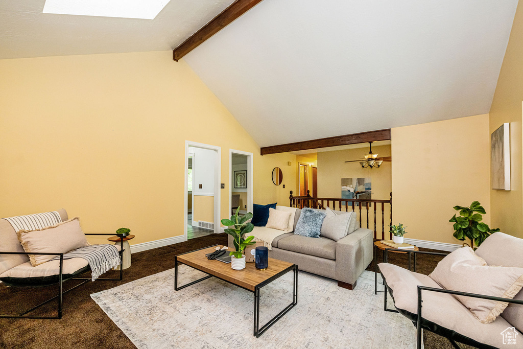 Living area featuring a skylight, high vaulted ceiling, beam ceiling, light carpet, and baseboards