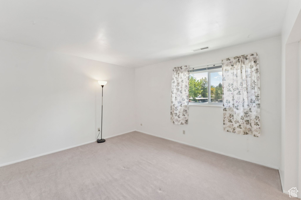Empty room with light carpet and baseboards