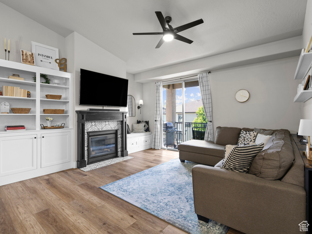 Living room featuring vaulted ceiling, a high end fireplace, ceiling fan, and light wood-type flooring